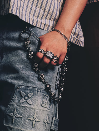 Stylish hand showcasing the D4RMD - SKULL CHAIN alongside trendy rings and denim, perfect for modern fashion.